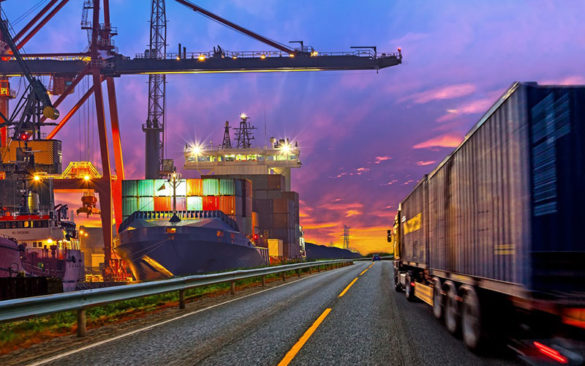 semi truck driving past a cargo shipping yard