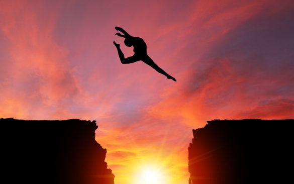 woman jumping over a ravine